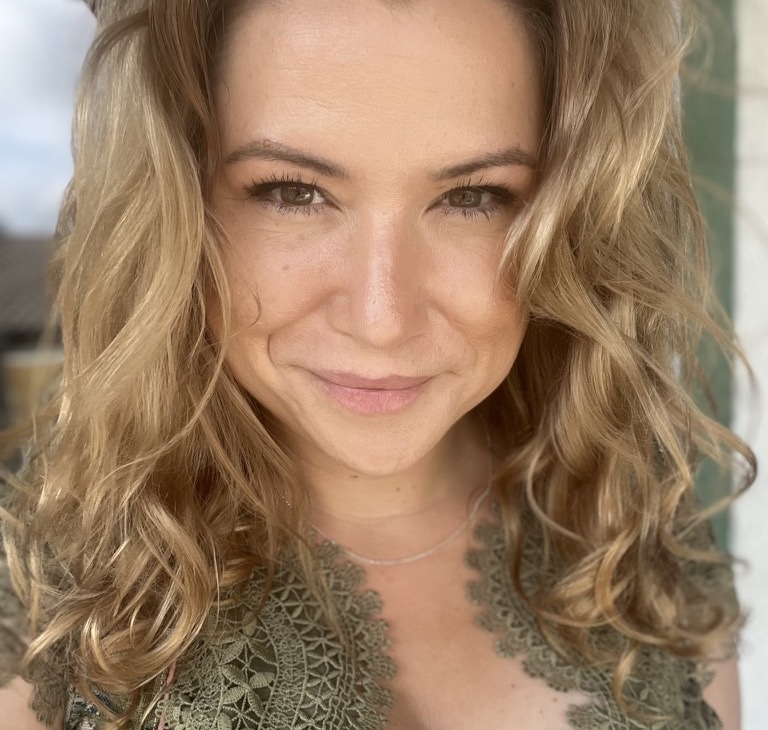Porträt von Sandra mit blonden Locken, sie lächelt in die Kamera