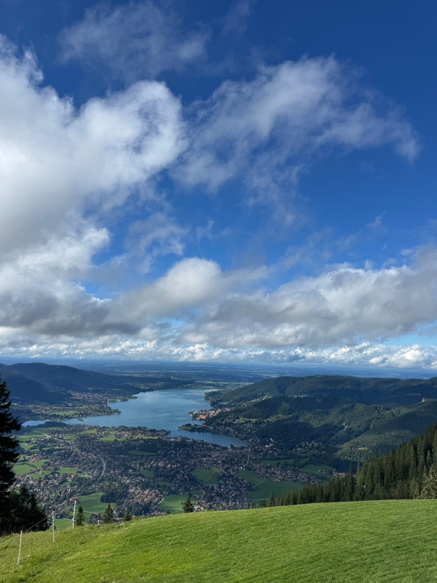 Blick vom Berg auf den Tegernsee unter weißen Wolken